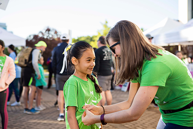 Girls on the Run coach helping to attach running bib on participants shirt